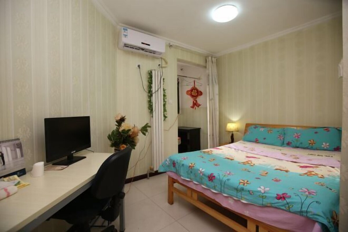 Ein Schlafzimmer mit einem Bett, einem Schreibtisch mit Computer und einer Klimaanlage.