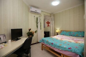A bedroom with a bed, a desk with a computer, and an air conditioning unit. - Zhengzhou Ruxinjia Apartment (Zhenghong Digital Apartment) (Zhengzhou)