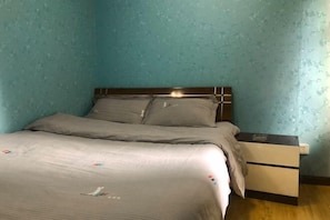 A bedroom with a bed, a nightstand, and a wall with a floral pattern. - Zhengzhou Ruxinjia Apartment (Zhenghong Digital Apartment) (Zhengzhou)