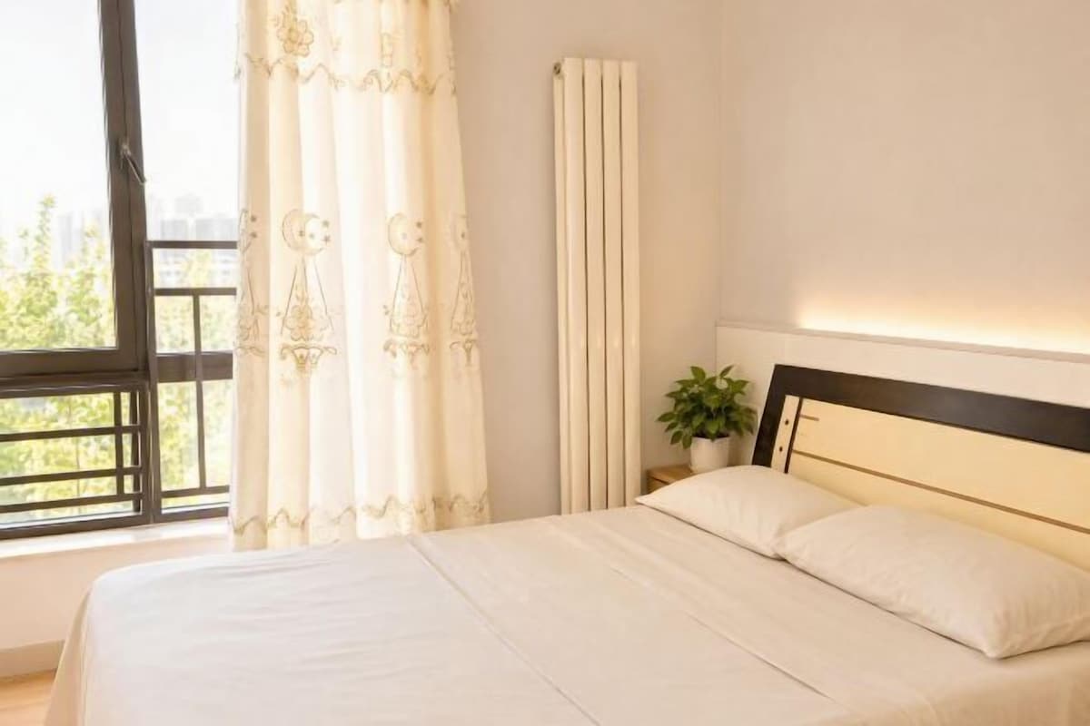 Un dormitorio con cama, cortinas, un radiador y una ventana.