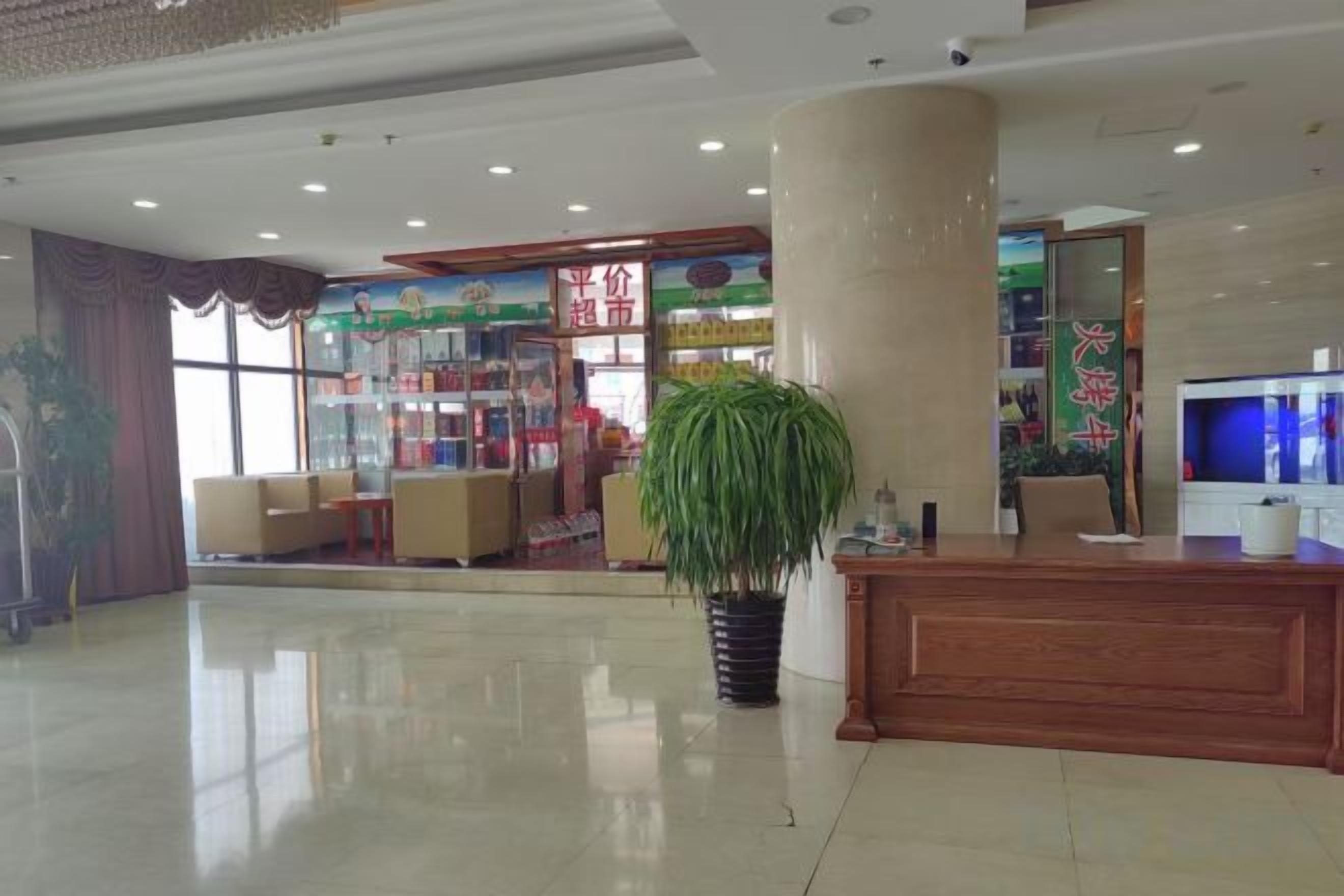 A hotel lobby with a reception desk, seating area, and a large potted plant.