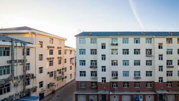A multi-story building with a central courtyard, multiple balconies, and a parking area.