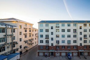 A multi-story building with a central courtyard, multiple balconies, and a parking area. - Times Lijing Hotel Xilinhot (Xilinhot)