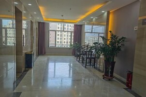 Un vestíbulo de hotel con piso de mármol, una escalera y grandes ventanales.