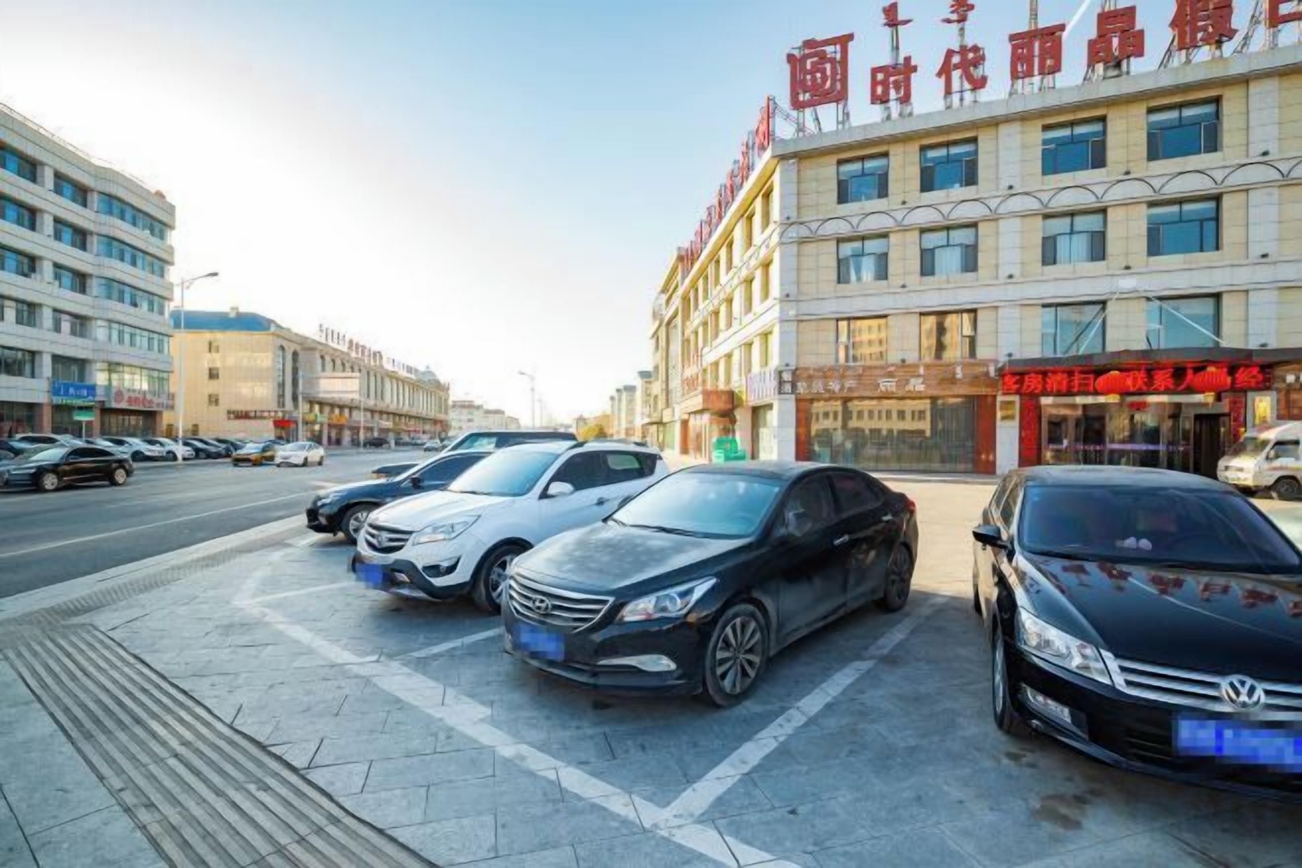 A parking lot with several cars, a building with signage, and a clear sky.