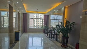Un vestíbulo de hotel moderno con piso de mármol, ventanas amplias y una escalera.
