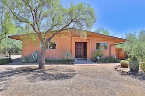 A single-story brick house with a front door, windows, and a small porch.