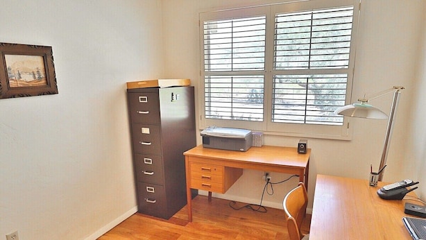 A room with a wooden desk, a filing cabinet, a window with blinds, and a desk lamp. - Happy Trails Hideaway (Tucson)