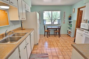 A kitchen with a dining table, chairs, a refrigerator, a microwave, and a window. - Happy Trails Hideaway (Tucson)
