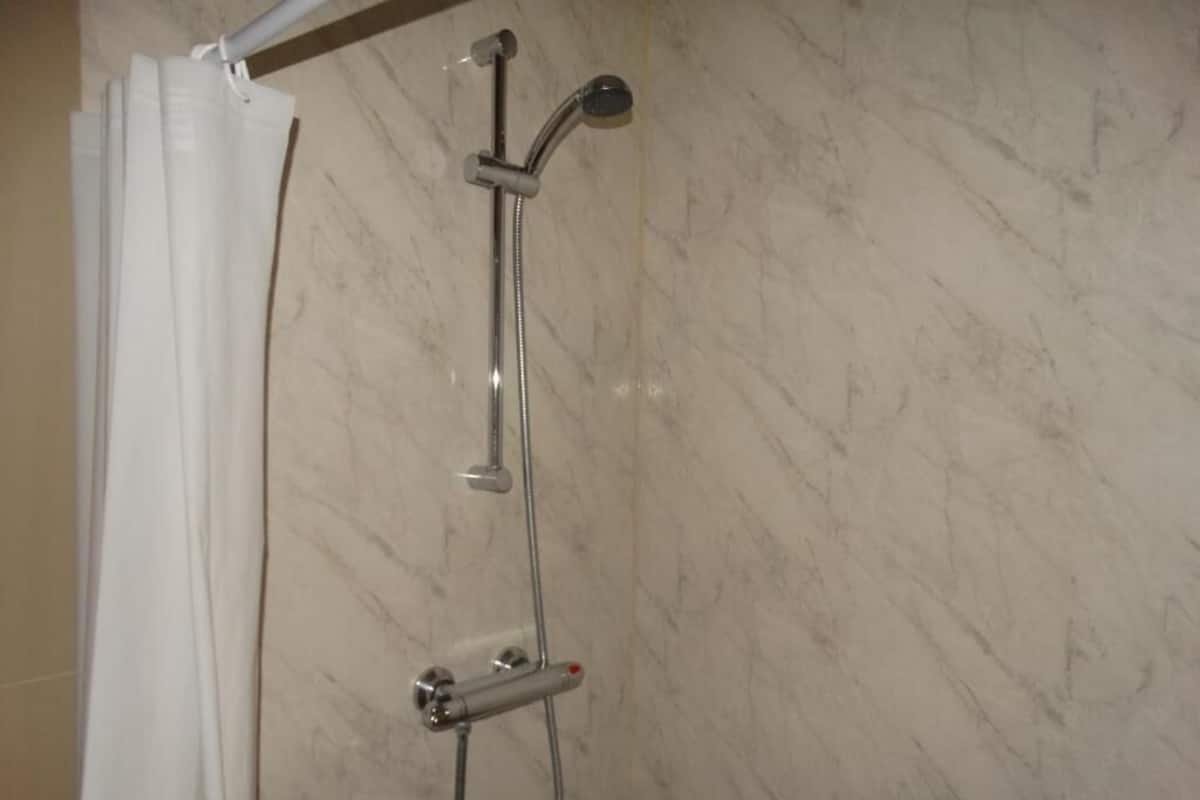Eenvoudige tweepersoonskamer | Badkamer | Een douche, handdoeken, toiletpapier