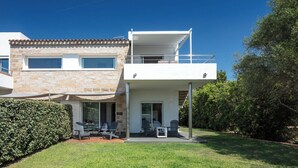 A modern two-story house with a patio area, outdoor seating, and a view of the surrounding greenery. - Sardegna è - Beach Rooms (Olbia)