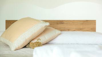 A bed with two pillows and a small pile of dried herbs.