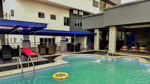 A swimming pool with lounge chairs and a covered seating area.