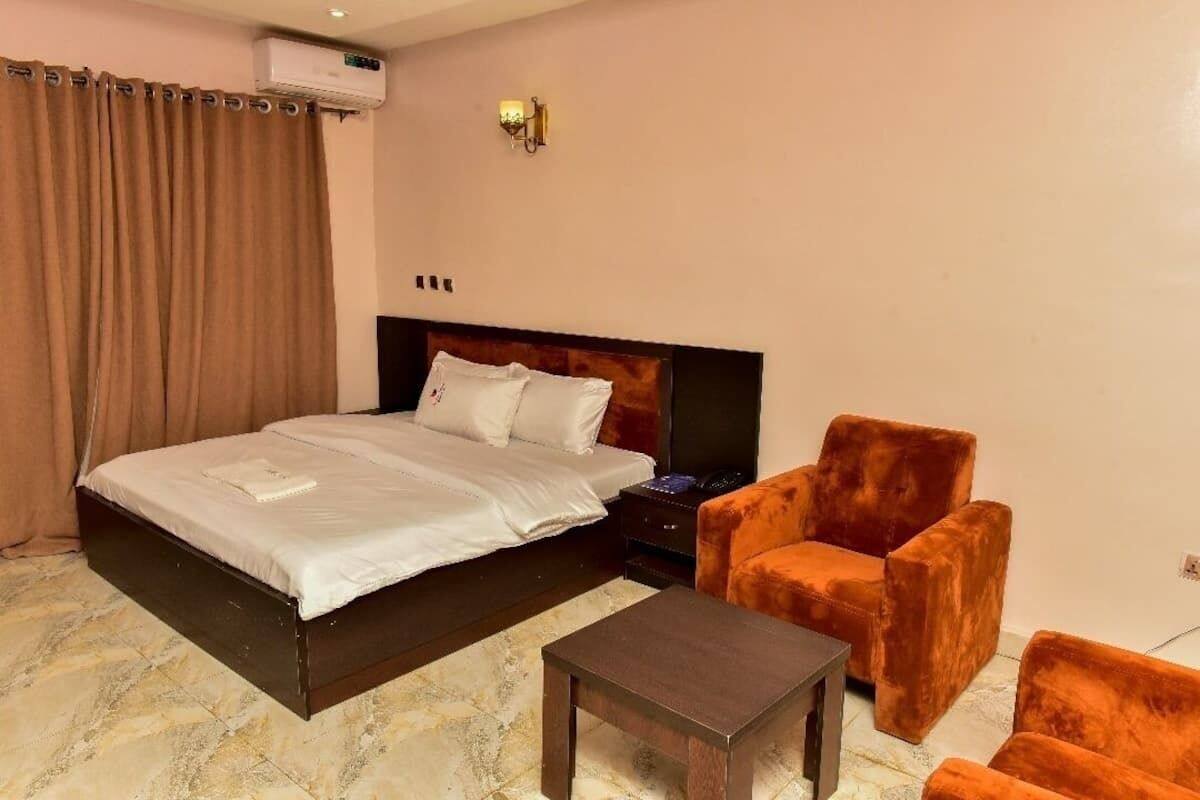 Un dormitorio con cama, mesita de noche, silla y una pequeña mesa.