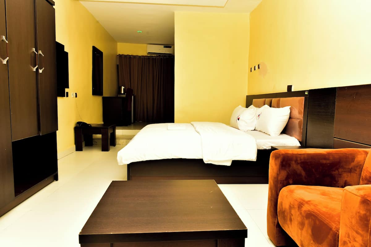 Habitación de hotel con cama, sofá, televisión y armario.