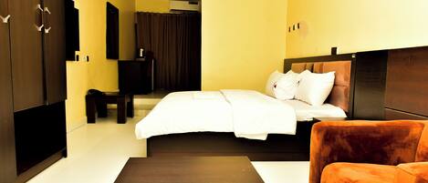 A hotel room with a bed, a sofa, a TV, and a wardrobe.