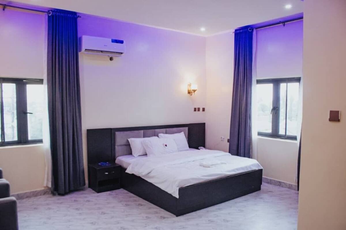 Un dormitorio moderno con una cama grande, un televisor de pantalla plana y aire acondicionado instalado en la pared.