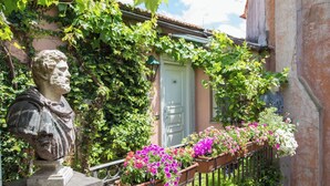 A statue of a man in a garden with a balcony, surrounded by lush greenery and flowering plants. - The Inn at the Roman Forum Elegant Collection - The Roman Forum Lodging. (Rome)