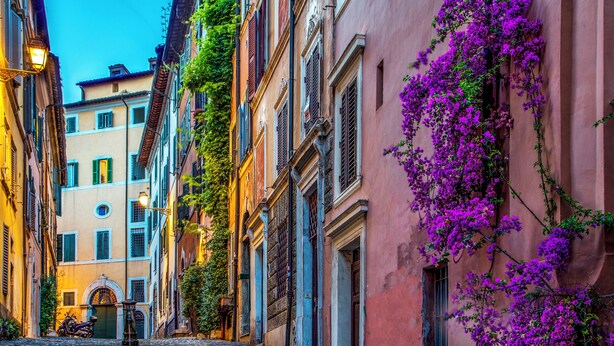 A narrow street with buildings on either side, steps leading up to a door, and a motorcycle parked at the bottom. - The Inn at the Roman Forum Elegant Collection - The Roman Forum Lodging. (Rome)