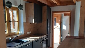 A modern kitchen with wooden cabinets, a built-in oven, and a large countertop.