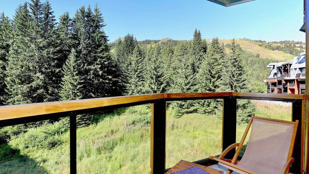 Ein Balkon mit Holzgeländer, Staffelei aus Leinwand und ein Buch mit dem Titel 'HOME'.