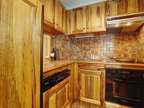 A kitchen with wooden cabinets, a Bosch dishwasher, a stove, and a tiled backsplash.