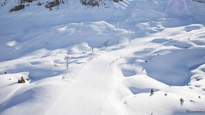 Eine verschneite Berglandschaft mit Seilbahnen und blauem Himmel.