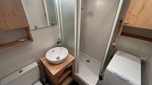 Ein kleines Badezimmer mit Waschbecken, Toilette und Dusche, alles in Weiß.