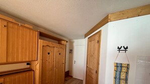 Ein Holztisch mit Stühlen, eine Küchenzeile mit Holzschränken und eine Tür mit einem Hahn-Verzierung.