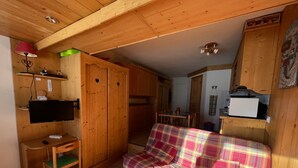 Ein gemütliches Zimmer mit einem karierten Sofa, Holzmöbeln, einem Fernseher und einer Mikrowelle.