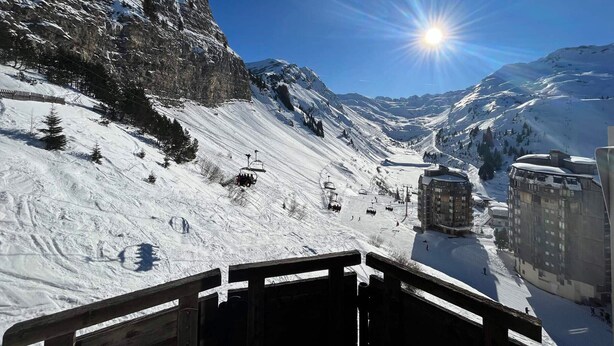 Eine verschneite Berglandschaft mit Seilbahn, Gebäuden und blauem Himmel.