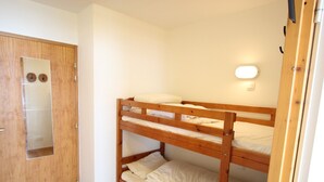 A bunk bed room with a wooden door and a small mirror.