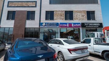 A building with a sign for 'Aljabir Laundry' and '30 Degrees Barbershop'. There are cars parked in front.