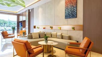 Un lobby moderno con un sofá, sillas, una mesa de centro y una planta.