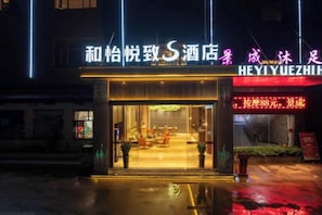 A hotel entrance with a visible reception area and a signboard.