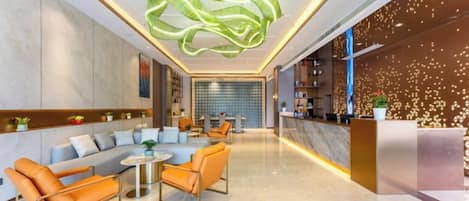 A modern lobby with a reception desk, seating area, and a decorative ceiling light.