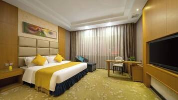 A hotel room with a bed, desk, chair, TV, and curtains.