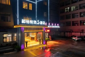 A hotel with a neon sign, a wet ground, and a parked car. - Heyiyuezhi S Hotel (Dongguan Fenggang Town People's Hospital Yongsheng Street) (Dongguan)