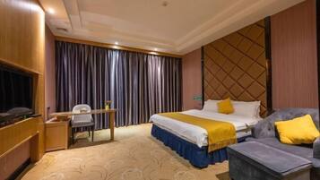 A hotel room with a bed, a sofa, a TV, a desk, and a curtain.