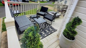 A deck with outdoor furniture, a potted plant, and a view of a residential area. - The Westwood at Percy Wood (Morpeth)