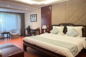Een hotelkamer met een groot bed, een bureau, een stoel en een raam met gordijnen.