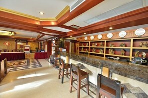 Un hall de hotel con mostrador de recepción, zona de bar y asientos.
