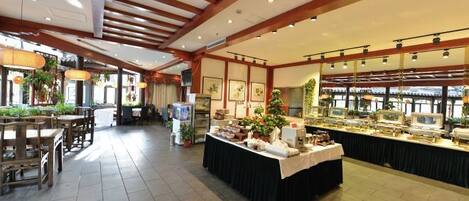 A spacious hotel lobby with a central island, dining area, and a view of the city.