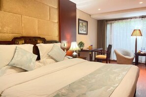 Een hotelkamer met een groot bed, een bureau, een stoel en een lamp.