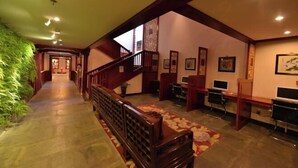 A hallway with a wooden staircase, desks, chairs, and framed pictures on the walls. - Oriental Zeng Hotel (Beijing)