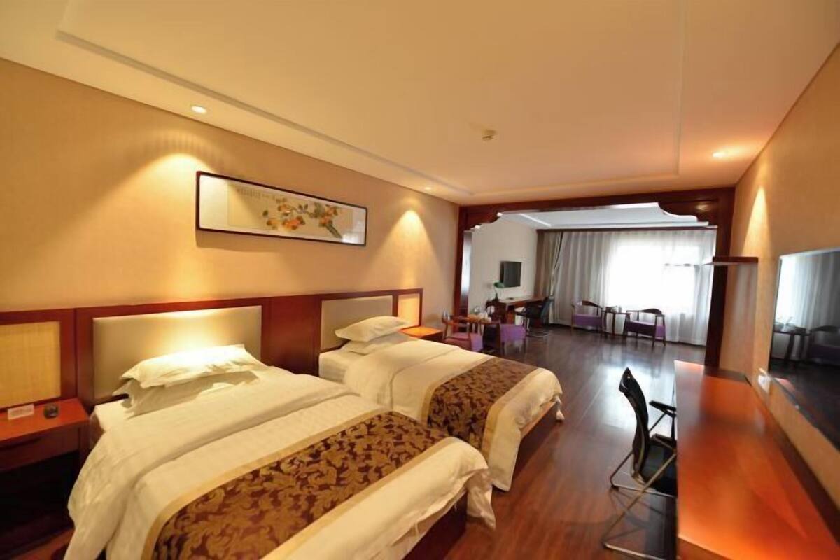 Une chambre d’hôtel avec deux lits, un bureau, une chaise et un téléviseur.