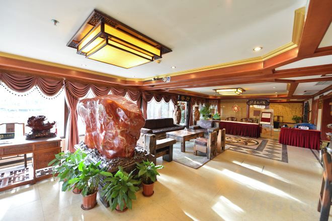 A spacious lobby with a large rock centerpiece, potted plants, and a reception desk.