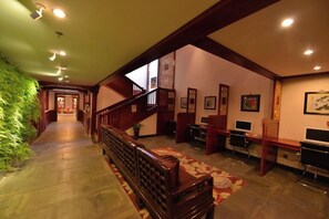 Een hotellobby met een houten trap, een zithoek en een receptiebalie.