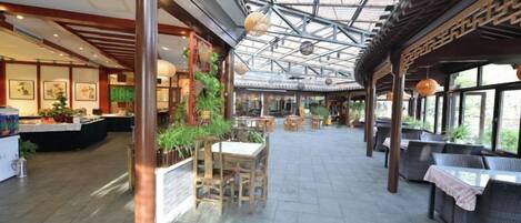 An indoor dining area with a high ceiling, wooden beams, and tables and chairs.