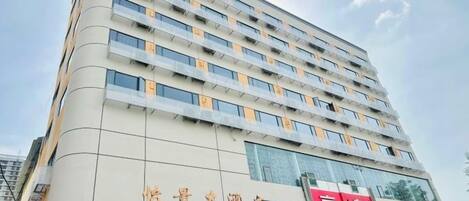 A multi-story hotel building with a modern architectural design, featuring a prominent signboard at the ground level.
